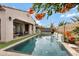 Relaxing backyard featuring a pool with water features, covered patio, and lush greenery at 22854 E Sonoqui Blvd, Queen Creek, AZ 85142