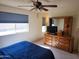 Comfortable bedroom featuring a ceiling fan, dresser, and a window with blue blinds at 2839 W Villa Maria Dr, Phoenix, AZ 85053