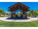 Community outdoor seating area with a pergola, table, and chairs, surrounded by green space at 4330 S Neutron --, Mesa, AZ 85212