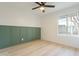 Neutral toned bedroom with wainscotting, modern ceiling fan and a large window at 4932 W Golden Ln, Glendale, AZ 85302