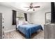 Neutral bedroom with wood-look floors, dark curtains, and a ceiling fan with lights at 5223 W Lewis Ave, Phoenix, AZ 85035