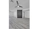 Spacious living room with light gray wood floors, light gray walls, black brick accent, and two fans at 5942 W Seldon Ln, Glendale, AZ 85302