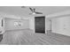 Spacious living room with light gray wood floors, light gray walls, black brick accent, and two fans at 5942 W Seldon Ln, Glendale, AZ 85302