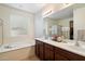 Elegant primary bathroom showcases double sinks, granite counters, large mirror, soaking tub, and ample natural light at 9010 W Ruth Ave, Peoria, AZ 85345