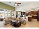 Open-concept living area with a large window, sofas, and a kitchen featuring dark wood cabinetry at 9010 W Ruth Ave, Peoria, AZ 85345