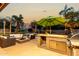Outdoor kitchen and seating area with palm trees and a pool in the background at 10105 E Larkspur Dr, Scottsdale, AZ 85260