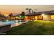 Landscaped backyard with pool, patio, grassy area and palm trees at dusk at 10105 E Larkspur Dr, Scottsdale, AZ 85260
