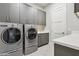 Well-equipped laundry room featuring stainless steel washer and dryer, cabinets, and a countertop with sink at 15921 E Ridgestone Dr, Fountain Hills, AZ 85268