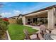 Inviting covered back patio featuring comfortable seating, lush green grass, and a cozy fire pit at 1752 N Harper --, Mesa, AZ 85207