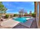 Backyard pool with stacked stone waterfall, concrete patio, and woodpile with mature desert landscaping at 208 S La Amador Trl, Casa Grande, AZ 85194