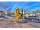 Community playground with yellow slide, climbing area and mature landscaping with bench seating in the background at 20867 N Grantham Rd, Maricopa, AZ 85138
