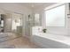 Bright bathroom featuring a tub with jets, glass shower, tile floors, and a large window at 21842 E Via De Olivos --, Queen Creek, AZ 85142