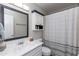 Cozy bathroom with a marble-look sink, black-framed mirror and cabinet, and shower with a gray curtain at 22102 W Ripple Rd, Buckeye, AZ 85326