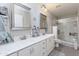 Bright bathroom featuring dual sinks, framed mirrors, and a glass-enclosed shower at 22102 W Ripple Rd, Buckeye, AZ 85326