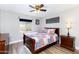 Bedroom with wood-look flooring, ceiling fan, window, and dark wood furniture at 22102 W Ripple Rd, Buckeye, AZ 85326