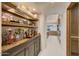 Elegant hallway bar featuring custom cabinetry and arched entry to the kitchen at 40915 N 107Th Pl, Scottsdale, AZ 85262