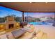 Inviting outdoor living area featuring a stone fireplace, plush seating, and stunning views of the pool and desert landscape at 40915 N 107Th Pl, Scottsdale, AZ 85262