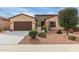 Charming tan home with a well-manicured desert-landscaped front yard and a brown two-car garage door at 41737 W Cribbage Rd, Maricopa, AZ 85138