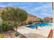 Sparkling pool with tranquil water feature, mature landscaping, and lush greenery offers a backyard oasis at 41737 W Cribbage Rd, Maricopa, AZ 85138