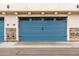 A blue garage door with black hardware, set in front of a brick and white wall at 4438 N 27Th St # 24, Phoenix, AZ 85016