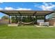 Backyard with artificial grass, fire pit, hammock, hot tub, and covered patio at 5172 S Seton Ave, Gilbert, AZ 85298
