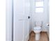 Neat powder room features a toilet and tile flooring next to a white door and a window at 9740 E Gold Dust Ave, Scottsdale, AZ 85258