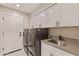 Laundry room featuring front load washer and dryer, modern white cabinets and gray countertop with stainless steel sink at 10435 N 98Th St, Scottsdale, AZ 85258