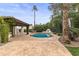 Inviting backyard pool with a stone tile deck, fireplace, pergola, and lush landscaping at 10435 N 98Th St, Scottsdale, AZ 85258