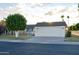 Charming single-level home featuring a two-car garage, mature trees, and manicured landscaping at 10523 W Roundelay Cir, Sun City, AZ 85351