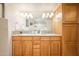 Bright bathroom features dual sinks with granite countertops, wood cabinets, and ample vanity lighting at 12212 N Paradise Village S Pkwy # 146, Phoenix, AZ 85032