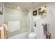Cozy bathroom with a glass-enclosed shower-tub combo, floral decor, and neutral tones at 12212 N Paradise Village S Pkwy # 146, Phoenix, AZ 85032