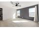 Minimalist bedroom featuring a dark accent wall, neutral carpet, and large windows with light curtains at 12673 W Myrtle Ave, Glendale, AZ 85307