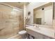 Bright bathroom featuring a marble-style shower, and a large mirror over a marble sink at 13640 N Del Webb Blvd, Sun City, AZ 85351