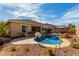 Backyard with a pool, rock waterfall, shaded seating area, and outdoor bar at 15062 W Windward Ave, Goodyear, AZ 85395