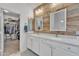 Bathroom featuring a double vanity, decorative wood wall, modern lighting, and a walk-in closet at 16847 W Marconi Ave, Surprise, AZ 85388