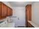 Well-lit laundry room featuring wooden cabinets, a utility sink, and a washing machine at 17405 N Conquistador Dr, Sun City West, AZ 85375