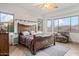 Stylish bedroom with a wooden bed frame, ceiling fan, and bright windows overlooking the landscape at 18391 W Verdin Rd, Goodyear, AZ 85338