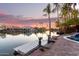 Beautiful backyard with a pool and lake view, lush landscaping, and picturesque sunset backdrop at 2043 E Clipper Ln, Gilbert, AZ 85234