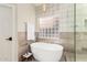 Modern bathroom featuring a freestanding soaking tub, glass block window, and neutral tile at 2043 E Clipper Ln, Gilbert, AZ 85234