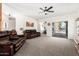 Carpeted living room with leather sofas, a ceiling fan, and sliding glass doors at 22236 E Nacoma --, Queen Creek, AZ 85142