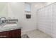 Clean bathroom with a granite sink, tiled floor, and a shower with a patterned curtain at 38145 W Amalfi Ave, Maricopa, AZ 85138
