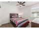 Simple bedroom with dark wood furniture, a ceiling fan, a window and carpeted floors at 38145 W Amalfi Ave, Maricopa, AZ 85138