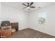 Empty bedroom with carpet floors, a ceiling fan, and a window. Boxes sit in a corner at 38145 W Amalfi Ave, Maricopa, AZ 85138