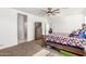 Spacious bedroom with a wooden bed frame, a ceiling fan, and an attached bathroom at 38145 W Amalfi Ave, Maricopa, AZ 85138