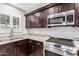 Close up of kitchen with stainless steel appliances, granite countertops, dark wood cabinets and tile floor at 4037 S Taylor Dr, Tempe, AZ 85282