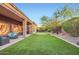 Lush backyard featuring a putting green, covered patio, mature trees, and well-maintained landscaping at 40930 N Lambert Trl, Phoenix, AZ 85086