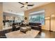 Bright and airy living room featuring a ceiling fan, dark hardwood floors, and an open layout to the kitchen at 40930 N Lambert Trl, Phoenix, AZ 85086