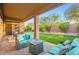 Relaxing covered patio with cozy seating, a fire pit, and a view of the lush backyard and putting green at 40930 N Lambert Trl, Phoenix, AZ 85086