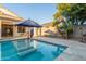Backyard pool with blue umbrella, travertine tile and tropical landscaping at 445 W Gary Ave, Gilbert, AZ 85233
