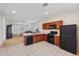 Open concept kitchen with wood cabinets and black appliances, flowing into a living area at 45734 W Sky Ln, Maricopa, AZ 85139